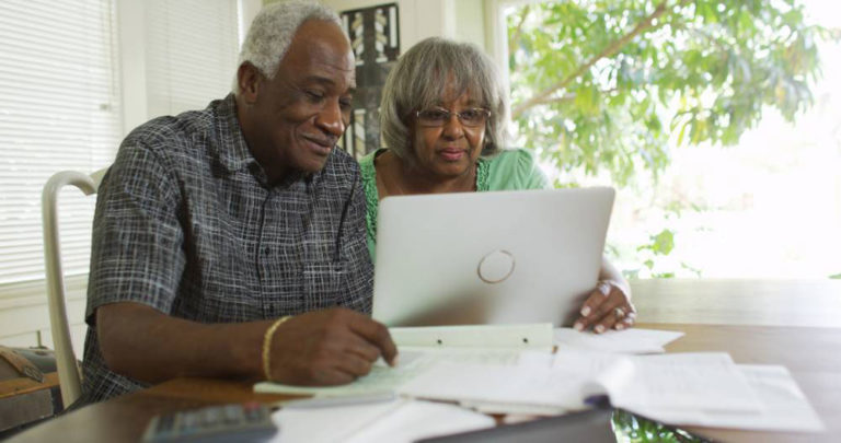 A senior couple using a laptop to go over finances.
