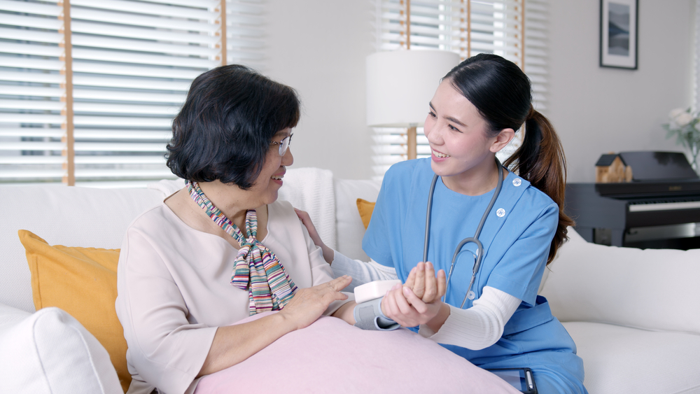 A health care professional checks in on a senior woman in short term rehabilitation
